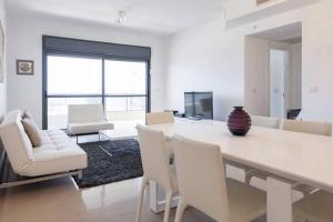 una sala de estar blanca con mesa y sillas en Netanya Family Apartment with Balcony by FeelHome, en Netanya