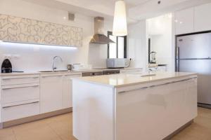 cocina grande con armarios blancos y nevera en Netanya Family Apartment with Balcony by FeelHome, en Netanya