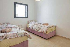 2 camas individuales en una habitación con ventana en Netanya Family Apartment with Balcony by FeelHome, en Netanya