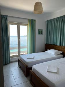 1 dormitorio con 2 camas y una ventana con vistas al océano en Menikos Apartments, en Himare