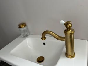 a white sink with a gold faucet on it at Lovisas Stuga in Vadstena