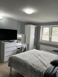 a bedroom with a bed and a desk and a television at Pokoje gościnne U Sylwii in Jarosławiec