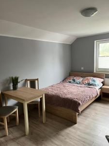 1 dormitorio con cama y mesa de madera en Pokoje gościnne U Sylwii, en Jarosławiec