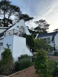 a white house with a balcony on top of it at Chez Botanica Apartment Constantia in Cape Town