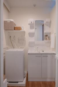 uma casa de banho branca com um lavatório e um espelho em RIVER VILLAS HIROSHIMA - Vacation STAY 24194v em Hiroshima