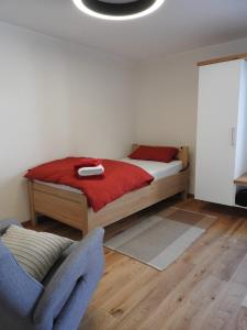 1 dormitorio con 1 cama con sábanas rojas y silla en Einzel- Monteurzimmer barrierfrei en Forchtenberg