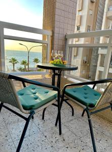 dwa krzesła i stół z misą owoców na balkonie w obiekcie Sea breeze w mieście Bat Jam