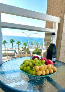 a plate of fruit on a table with wine glasses at Sea breeze in Bat Yam