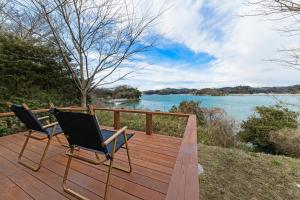 2 Stühle auf einer Terrasse mit Flussblick in der Unterkunft Hermitage Resort Matsushima hibiki - Vacation STAY 14654 