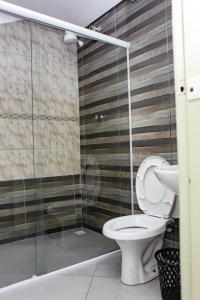 a bathroom with a toilet and a glass shower stall at Hotel Tenda Jaçanã in São Paulo