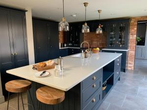 uma cozinha com um balcão branco e armários azuis em Luxury Barn conversion, 3 bed, 3 bath with hot-tub em Bedford