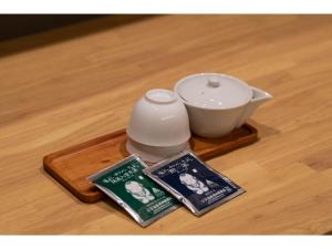 Hotel Celeste Shizuoka Takajo - Vacation STAY 94075v في شيزوكا: ابريق شاي وكتب على صينية خشبية