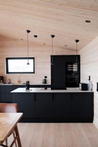 a kitchen with black cabinets and a counter top at Ekkerøy Lodge - Arctic living in Vadsø