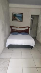 uma cama num quarto com piso branco em Pousada Lambaris Pereque Guarujá no Guarujá
