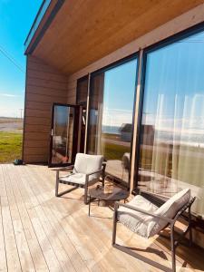 Ekkerøy Lodge - Arctic luxury في فادسو: وسطح مع كرسيين واريكة على بيت