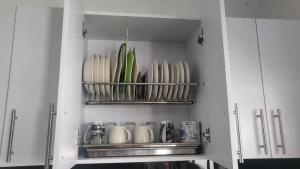 una cocina con armarios blancos y una estantería con tazas en Bello apartamento familiar en Pitalito en Pitalito