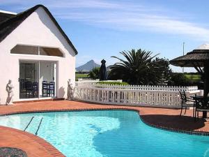 a swimming pool in front of a white fence at Lagoon Lodge in Cape Town