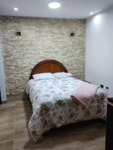 Ce lit se trouve dans une chambre dotée d'un mur en briques. dans l'établissement Casa de Juli, à Huancayo