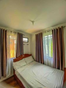 a bedroom with a bed and windows with curtains at 3 Bedroom Furnished House near SM CDO uptown in Cagayan de Oro