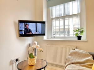 a television hanging on a wall in a living room at Spacious 2 Bedrooms Flat Archway Station in London