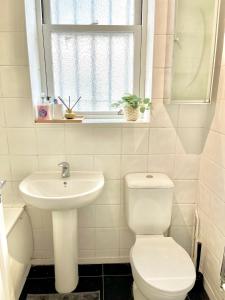a bathroom with a toilet and a sink and a window at Spacious 2 Bedrooms Flat Archway Station in London