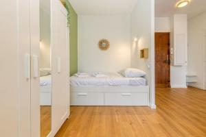 a bedroom with a bed with white walls and wooden floors at Entre gare et centre-ville: lit double, wifi in Grenoble