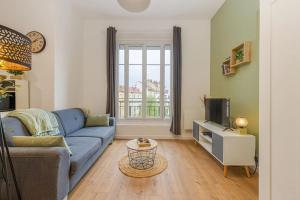 ein Wohnzimmer mit einem blauen Sofa und einem TV in der Unterkunft Entre gare et centre-ville: lit double, wifi in Grenoble