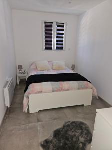 a white bedroom with a bed and a window at Bas de villa au calme in Marseille