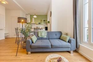 a living room with a blue couch and a kitchen at Entre gare et centre-ville: lit double, wifi in Grenoble