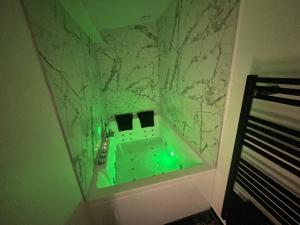 bagno con vasca verde e parete in marmo di Le cocon Balnéo a Sens
