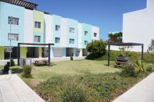 um grande edifício de apartamentos com um quintal com bancos em Beach Vibes 72 Gardenhaus em Tijuana
