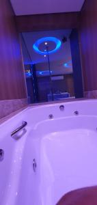 a white bath tub in a bathroom with a blue light at Motel Fantasy 3 (Adult Only) in Belo Horizonte