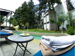 un patio con mesa y sillas junto a una piscina en Hotel Boutique Camino Del Bosque by Rotamundos, en Cholula