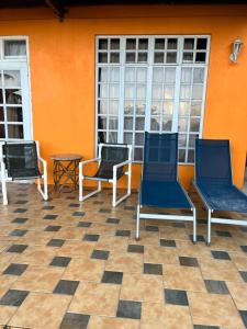 3 sedie sedute su un portico con parete arancione di Ocean Views and Hospitable Hosts a Castries
