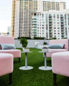 a patio with pink couches and tables on the grass at Brickell Bliss - Luxury Condo in Miami