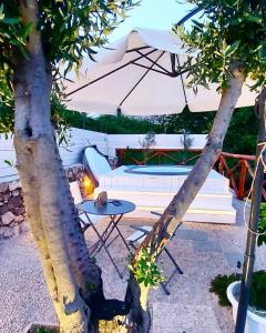 eine Terrasse mit einem Tisch und einem Sonnenschirm in der Unterkunft FOUR WHITE APARTMENTS in Agerola