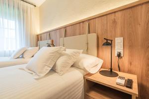1 dormitorio con 2 camas, almohadas blancas y lámpara en Hotel R Santillana, en Santillana del Mar