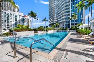 a swimming pool with palm trees and buildings at Brickell Bliss - Luxury Condo in Miami