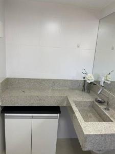 eine Küchentheke mit einem Waschbecken und einem Spiegel in der Unterkunft Casa em condomínio a 50mt da praia dos ossos in Búzios + 18 Fotos