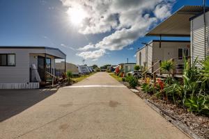 a road between two houses with the sun in the sky at Magnolia Village Caravan Park in Hervey Bay