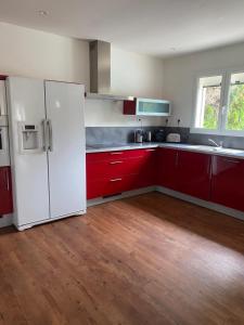 uma cozinha com armários vermelhos e um frigorífico branco em Villa Jurio em Argeliers