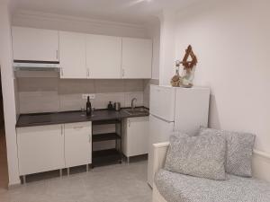 a kitchen with white cabinets and a refrigerator and a couch at Apartamentos As de guía, playa de las canteras in Las Palmas de Gran Canaria
