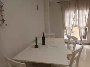 a white table with a bottle of wine and two chairs at Apartamentos As de guía, playa de las canteras in Las Palmas de Gran Canaria
