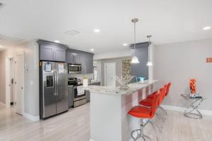 una cocina con electrodomésticos de acero inoxidable y taburetes de barra roja en Y&M TAMPA SWEET HOME! en Tampa