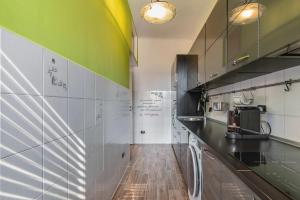 une cuisine avec des comptoirs noirs et un mur vert dans l'établissement Easylife - Coccole e relax nel cuore di Isola, à Milan