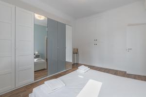 Cette chambre blanche comprend un lit et un miroir. dans l'établissement Easylife - Coccole e relax nel cuore di Isola, à Milan