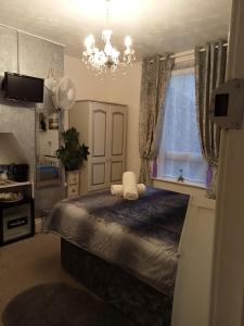 um quarto com uma cama com um lustre e uma janela em Marjune Guest House em Weymouth