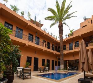 a hotel with a palm tree and a swimming pool at Hotel Toulousain in Marrakech