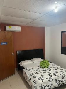 Un dormitorio con una cama con una almohada verde. en Hostal Kaia, en Santa Marta