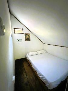 Un pequeño dormitorio con una cama blanca en una habitación en Hostal Kaia, en Santa Marta